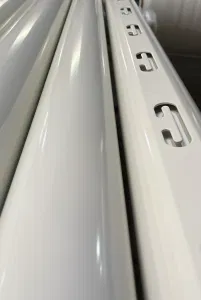 Weiße Metallschienen mit Langlöchern in Nahaufnahme